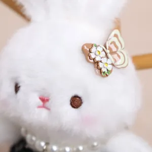 Primo piano dettagliato del ciondolo con coniglietto di peluche bianco e collana di perle.
