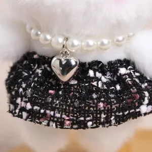Primo piano dettagliato di un peluche di coniglio con collana di perle e gonna in tweed chic.