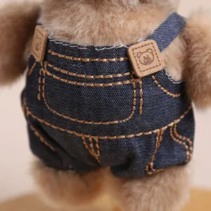 Dettaglio ravvicinato di simpatico orsetto di peluche con salopette in denim e bottoni.