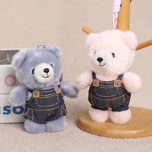 Primo piano dettagliato di grazioso portachiavi orsetto di peluche con salopette, borsa.
