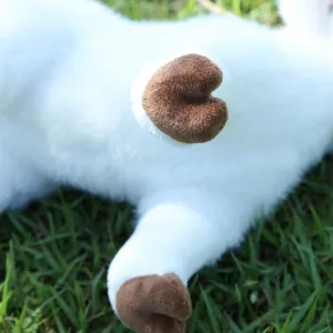 Close-up detail of simulation goat plush toy, soft white fur and brown hooves, fluffy texture.