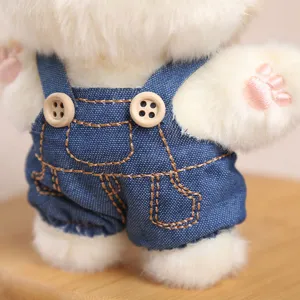 Close-up detail of cute overall kitten plush pendant with denim overalls and wooden buttons.