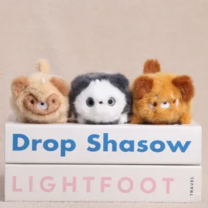 Gros plan de trois adorables pendentifs en peluche douce disposes sur des livres decoratifs.