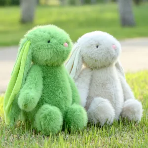 Detailed outdoor scene showing two soft plush bunny toys in green and white sitting on green grass.