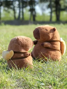 Nahaufnahme des süßen Wasserschwein Plüschtiers mit Brot Rucksack im Gras auf der Wiese.