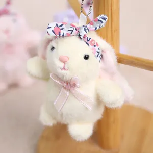 Primer plano detallado del colgante de conejito de peluche con diadema floral y lazo rosa.