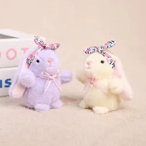 Detalle de llavero de conejo de peluche, tierno conejito con diadema floral y lazo rosa.