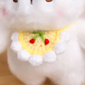 Gros plan détaillé d'un adorable porte-clés lapin en peluche blanche avec un bavoir tricoté.