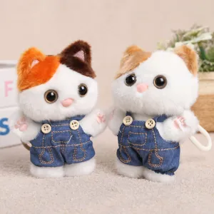 Close-up detail of cute plush cat keychains wearing denim overalls, soft toy pendant.
