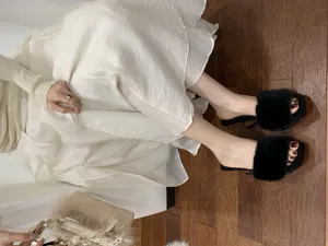 Detailansicht eleganter schwarzer flauschiger Pantoletten mit offener Zehenpartie im Herbst.