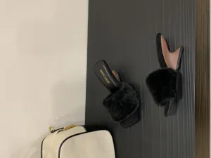 Detailaufnahme schwarzer Pantoletten mit Fell, quadratischer Zehenpartie und Keilabsatz.