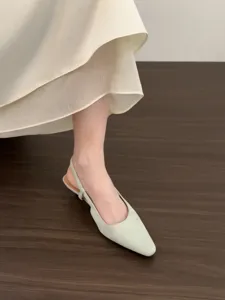 Close-up of elegant pointed toe slingback low-heel sandals in sage green suede material.