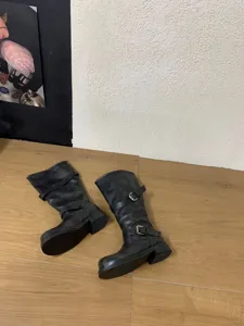 Gros plan de bottes souples noires mi-hautes avec brides à boucles et talons épais.