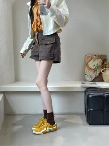 Detail view of retro yellow casual trainer shoes styled with socks and shorts for women daily wear.