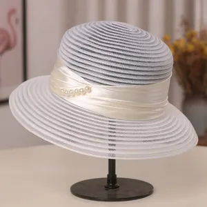 Gedetailleerd overzicht van elegante witte mesh zonnehoed met satijnlint en parels.