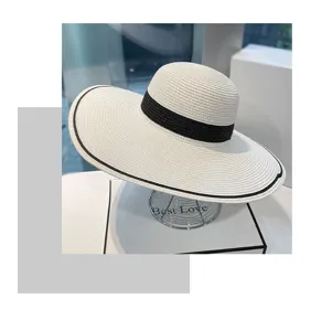Dettaglio del cappello da sole in paglia bianco elegante con nastro nero.