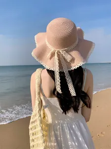 Détail chapeau de paille estival avec dentelle, bord ondulé et nœud élégant pour plage.