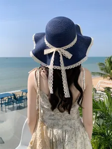 Vue de détail d'un chapeau de paille bleu marine avec nœud en dentelle blanche et chic.