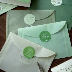 Ensemble de papeterie vert rétro avec enveloppes dorées à chaud, cartes et autocollants.