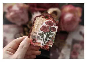 Closeup detail of retro journal scrapbooking sticker tag with vintage rose design and pearls.