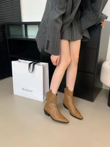 Detailed shot of brown pointed-toe western cowboy boots paired with a chic grey suit.