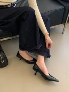 Detail close-up of women pointed toe kitten heel dress shoes worn with wide leg denim pants.