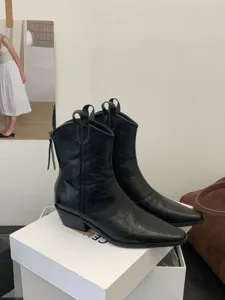 Detail view of black leather pointed toe chunky heel western short boots with vintage style.
