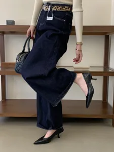 Detailed view of women's elegant black pointed-toe kitten heel shoes, styled with wide jeans.