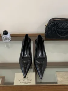 Close-up of elegant black pointed-toe kitten heel pumps displayed on a glass shelf with props.