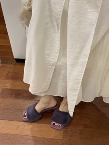 Nahaufnahme von lila flauschigen Pantoletten mit offener Zehenpartie für Damen, elegant.