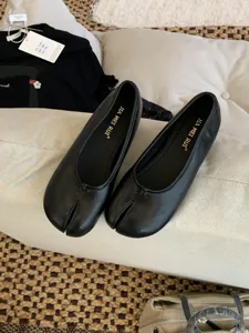 Vista detallada de zapatos Mary Jane negros con punta dividida, estilo retro y finos acabados.