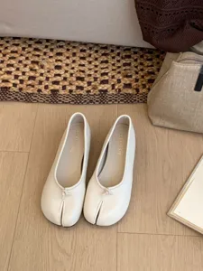 Primer plano detalle de los zapatos Mary Jane blancos punta dividida y lazo cuero