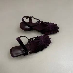 Detailed view of elegant purple velvet strappy sandals, stylish low heel shoes for summer.