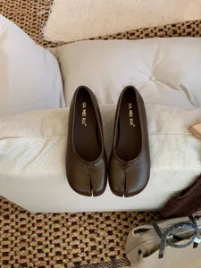 Detalle de zapatos planos Mary Jane marrones con punta partida, estilo vintage de cuero suave.