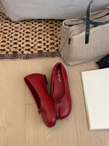 Vista detallada de elegantes zapatos mary jane rojos con punta dividida y suelo de madera.