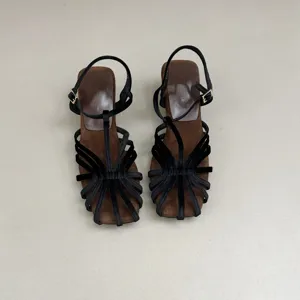 Closeup detail of women black velvet multi-strap high heeled sandals with brown insole.