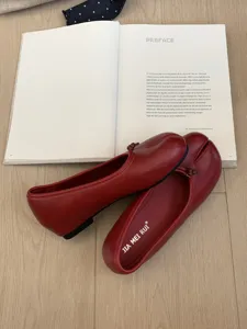 Detalle de zapatos Mary Jane rojos con punta dividida y elegante lazo de cuero suave.