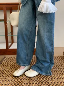Primer plano de zapatos planos Mary Jane blancos con punta partida para mujer con vaqueros.