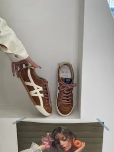Detailed close-up view of women casual brown suede flat trainer shoes with white side stripes