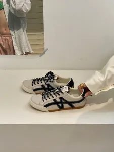 Casual women's leather trainer shoes in beige with black contrast side pattern and flat sole.