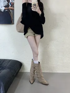 Close-up detail of stylish suede pointed-toe knee-high boots with multi-buckle design.