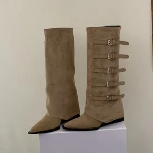 Suede knee-high boots detail showing pointed toe and multiple buckle straps design.