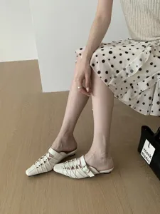 Dettaglio di eleganti sabot da donna con cinturini intrecciati e tacco basso.