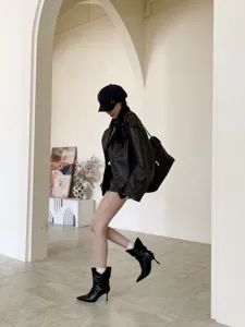 Primer plano detalle de elegantes botas negras puntiagudas de tacón de aguja mujer.