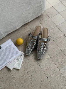 Vista dettaglio di mules argentate metallizzate con cinturini e design traforato basso.