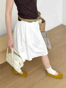 Vue détaillée de ballerines jaunes en daim à bout fendu, associées à des chaussettes blanches.