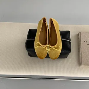 Close-up of yellow velvet ballet flats featuring delicate bow detail and comfortable flat sole.