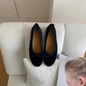 Dark blue velvet ballet flats featuring a delicate bow detail, comfortable flat shoes close-up.
