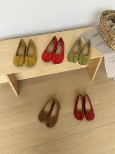 Vue détaillée de ballerines plates colorées à bout fendu présentées sur un banc en bois.