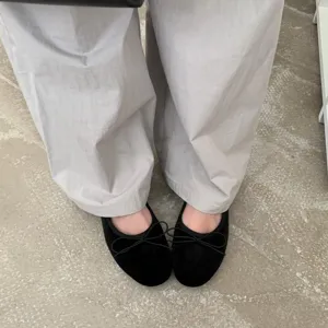 Black velvet ballet flats worn with gray pants, showcasing comfortable everyday footwear style.